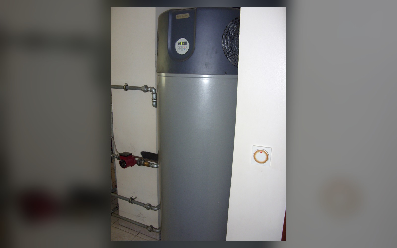 Heat-pump water heater installed in a utility area with clear space around the unit