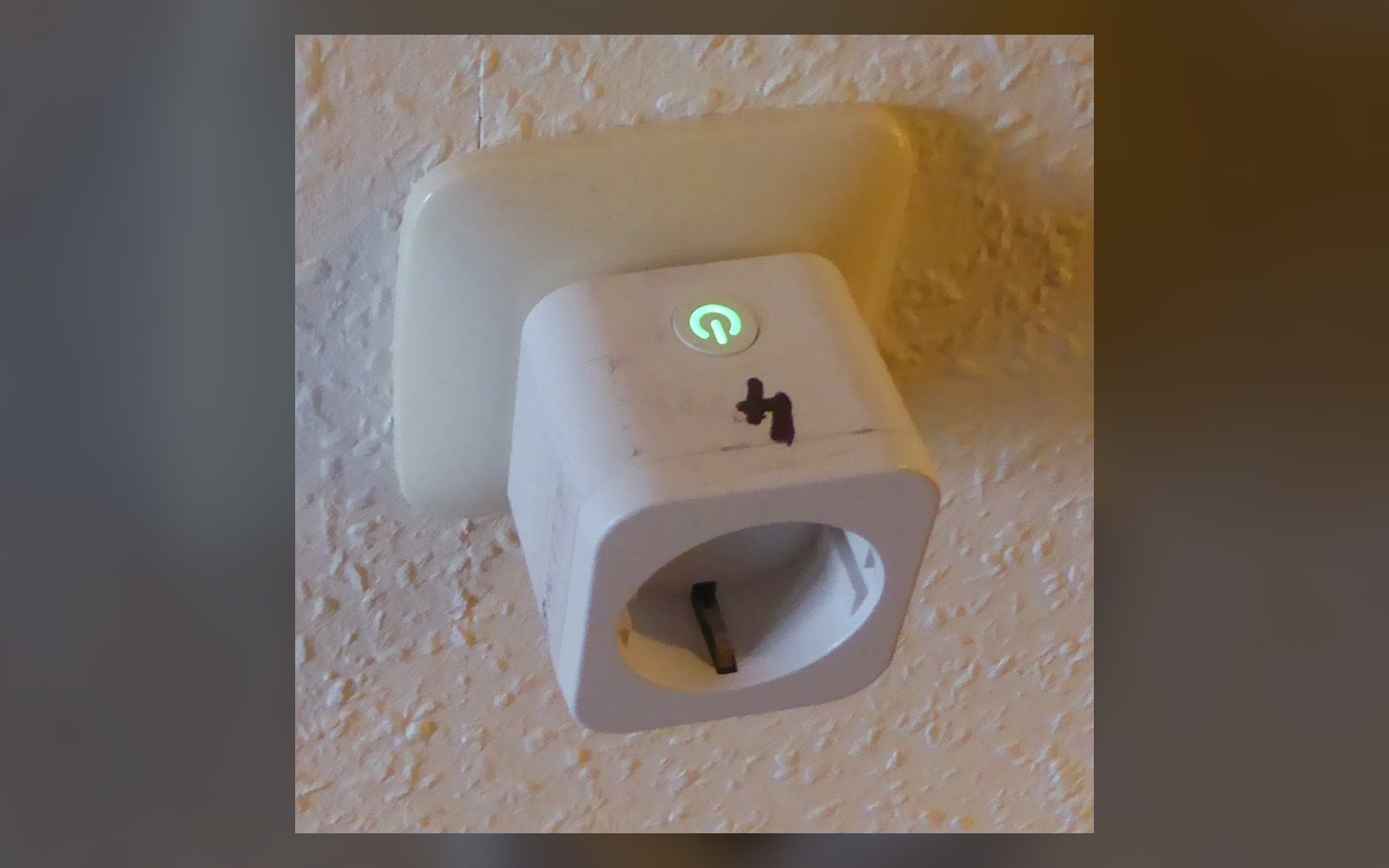 Wi-Fi smart plug installed in a wall outlet with its status light illuminated