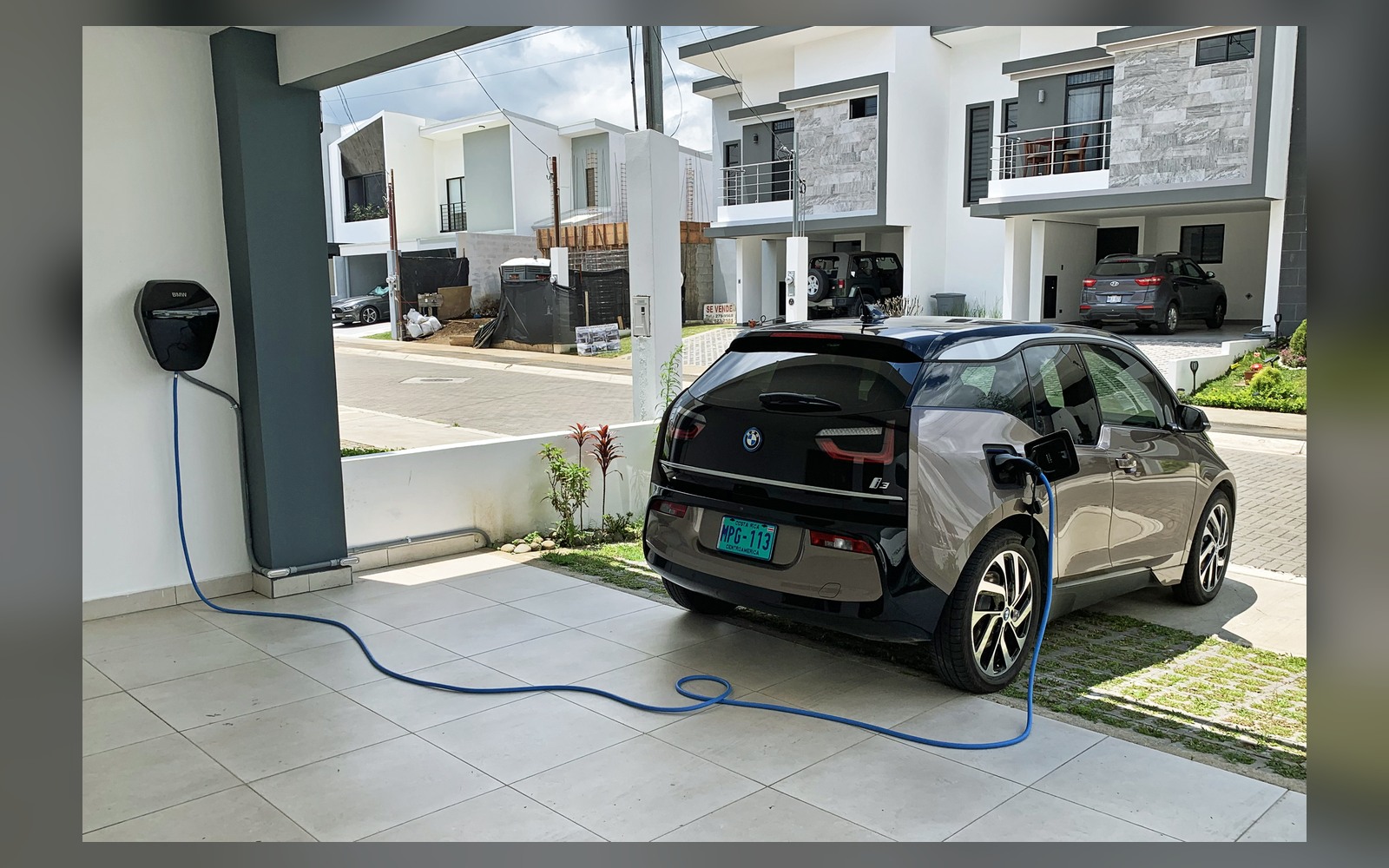 Electric vehicle charging on a residential driveway beside a modern home