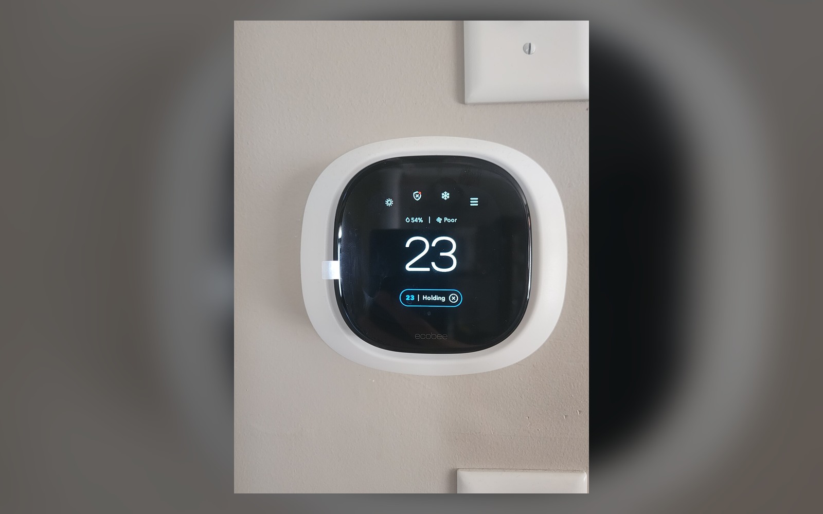 Wall-mounted smart thermostat showing temperature, humidity and system status